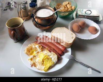 Food for breakfast on table boiled and fried eggs sausages bread Stock Photo