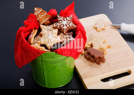 Idea DIY Do it yourself new year and Christmas gift concept butter sugar cookies with royal icing decoration in green bucket with copy space Stock Photo