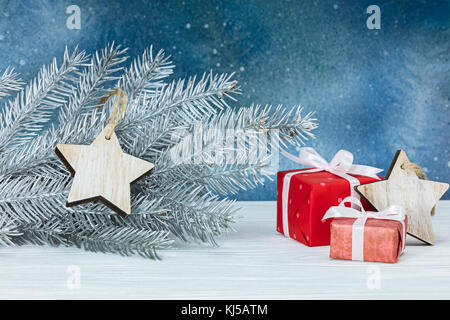 decorated silver christmas tree branch and gift boxes on blue festive background Stock Photo