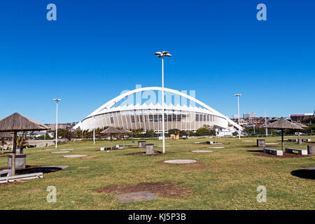 Grass lawn recreational area against Moses Mabhida stadium and blue sky in Durban, South Africa Stock Photo