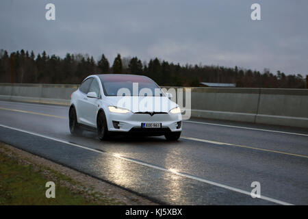 SALO, FINLAND - NOVEMBER 18, 2017: White Tesla Model X electric car moves along wet road in the evening. Stock Photo
