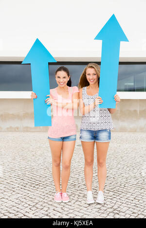 Teenage students holding blue arrows and pointing in diferent directions Stock Photo
