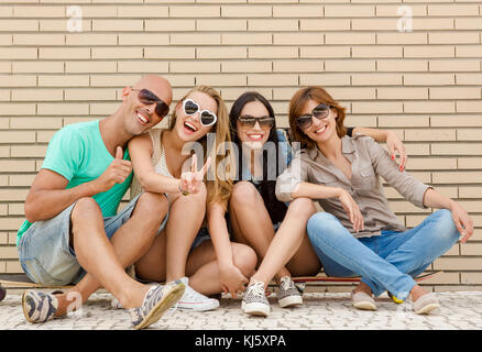 Group of friends posing in front of a brick wall Stock Photo