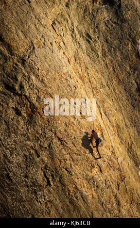 Male rock climber struggles for his next grip on the steep cliffs of Point Dume, Malibu, California Stock Photo