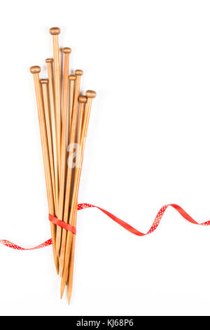 Wooden knitting needles and red and white polka dot ribbon on white background as frame Stock Photo