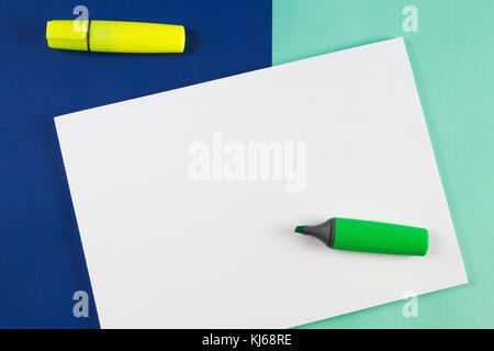 Yellow and green highlighters markers with blank sheet of paper on blue background. Stock Photo