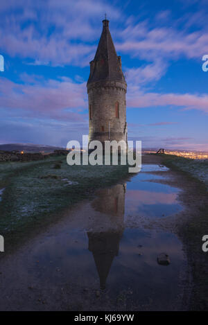 Hartshead Pike, Saddleworth is reflected in a puddle at sunset in April 2016. Stock Photo