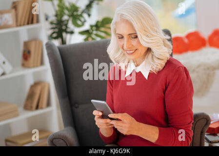 Positive minded lady using her smartphone at home Stock Photo