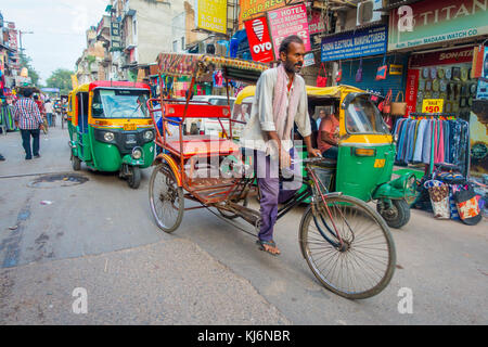 DELHI, INDIA - SEPTEMBER 25 2017: Unidentified man biking next to a Rickshaws parked in the streets and an auto-rickshaws in Paharganj, Delhi Delhi is the 2nd most populous city in India after Mumbai Stock Photo