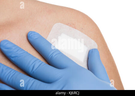 Doctor hand with surgical gloves checking patched surgery wound after female shoulder mole removal Stock Photo