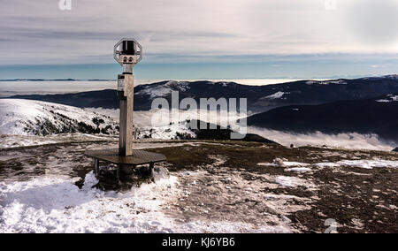 Binoculars on the top of a snowy mountain with a dramatic view in the background. Stock Photo