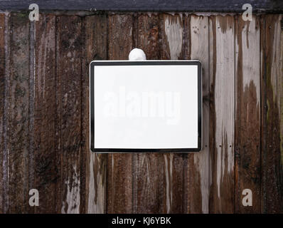 Blank white square sign on a frozen wall made of wooden planks. Stock Photo