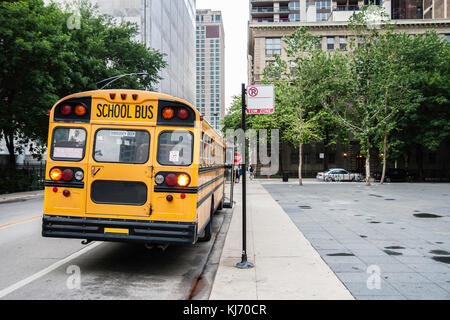 Rear view of a yellow school bus parked in downtown Chicago, waiting the end of the class with the front door open, USA. With copy space.
