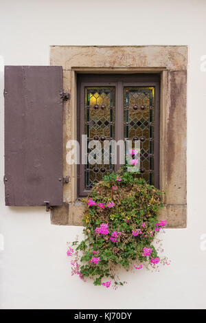 Old window made of stained glass. Style of central european Middle Ages. Wooden frame and wooden shutter. Structure made of stone. Stock Photo