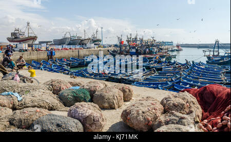 Essaouira, Morocco - September 15 2013: Blue wooden fishing boats anchored in historic port with seagulls and fishermen Stock Photo