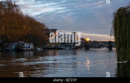 Autumn sunset, Thames River, Hampton Wick, looking West up river towards Kingston bridge, London, England, UK, with barges and water reflections Stock Photo