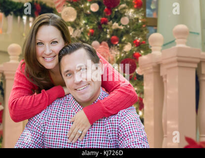 Caucasian Couple Hugging In Front of Decorated Christmas Tree. Stock Photo