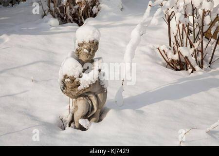 Garden cherub statuary in winter snow humour, Monroe Township, New Jersey, USA, United States, NJ snow fairy garden Stock Photo