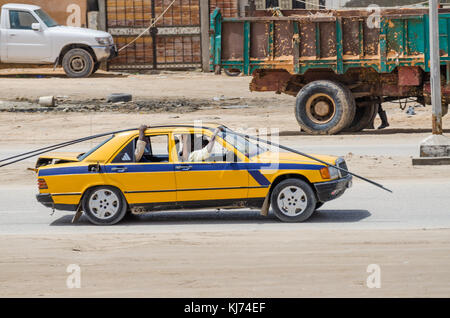 Nouakchott, Mauritania - October 08 2013: Street scene with steel rods transported by old taxi Stock Photo