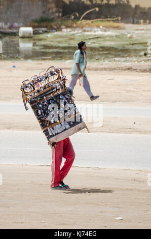 Nouakchott, Mauritania - October 08 2013: Street scene with sunglasses salesman walking down the road Stock Photo