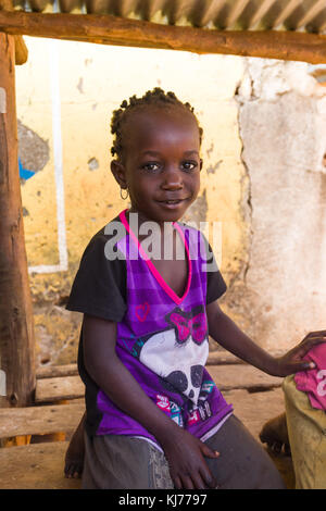 Young Ugandan girl sitting in the shade of an unused market stall, Uganda, Africa Stock Photo
