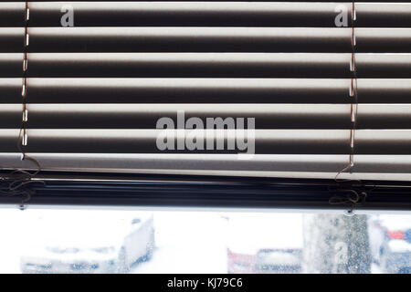 Fragment of the white Venetian blinds with lift cord and turning rod of a manual control on a foreground Stock Photo