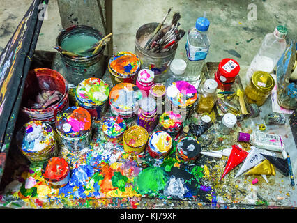 Brushes and cans of paint on a multicolored palette Stock Photo