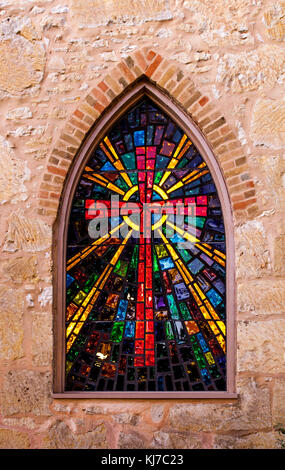 Gothic style church window with stained glass/ red cross made of stained glass Stock Photo