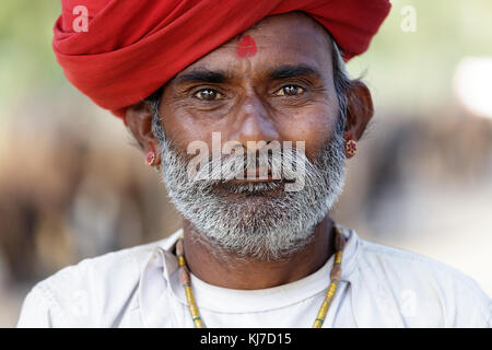 Portrait of a Rabari manwith moustaches dressed in traditional white clothes and red turban in countryside near Jodhpur, Rajasthan, India. Stock Photo