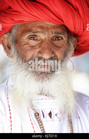 Portrait of a Rabari manwith moustaches dressed in traditional white clothes and red turban in countryside near Jodhpur, Rajasthan, India. Stock Photo