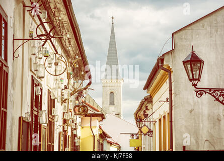 Hrnciarska street with Calvinist church in Kosice, Slovak republic. Folk art theme. Religious architecture. Yellow photo filter. Stock Photo