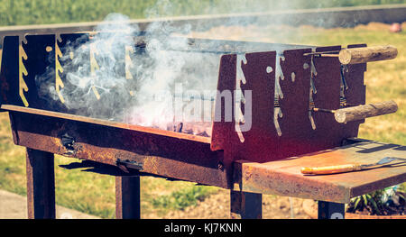 old rusty steaming barbecue when lighting in a garden Stock Photo