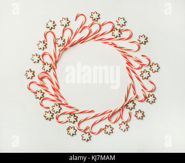 Christmas wreath pattern made up from candy cane sticks and star sugar cookies on white background, flat-lay, copy space Stock Photo