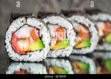 Sushi roll with salmon, shrimps and avocado over cocnrete background Stock Photo