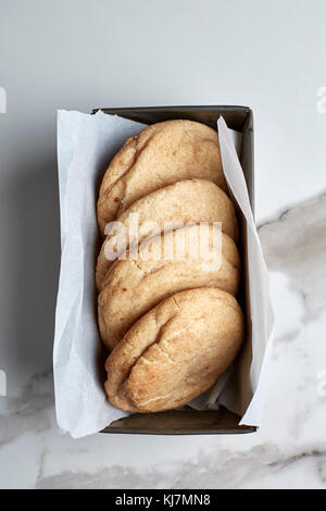 Snickerdoodle cookies in a vintage tin with parchment paper on white marble table Stock Photo