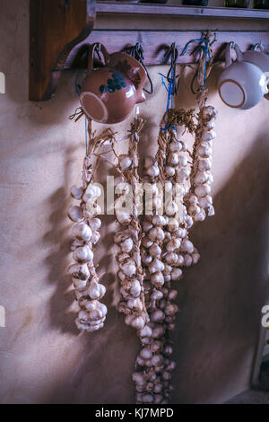 Garlic drying and hanging on the wall in rustic vintage kitchen Stock Photo