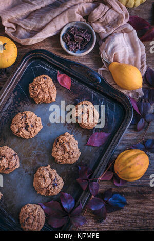 Pumpkin chocolate chip cookies on a baking tray on rustic wooden table Stock Photo