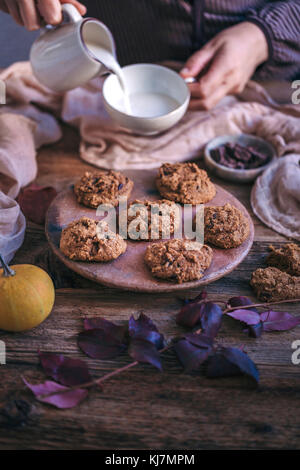 Woman eating pumpkin chocolate chip cookies with a cup of milk Stock Photo
