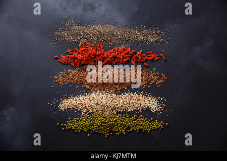 Superfoods and cereals selection for High Energy Lifestyle and Eating Right: chia seed, goji berry, flax seed, quinoa, mung bean on dark background Stock Photo