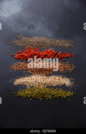 Superfoods and cereals selection for High Energy Lifestyle and Eating Right: chia seed, goji berry, flax seed, quinoa, mung bean on dark background co Stock Photo
