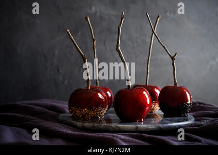 Marble tray of beautiful, red, candy apples on dark purple linen. Moody feel with dark textured background. Stock Photo