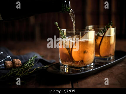 Whiskey cocktail with fresh thyme and pear on a rustic wood background. Stock Photo