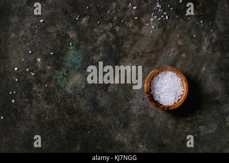 Olive wood bowl of sea salt over old dark metal background. Top view with copy space. Stock Photo
