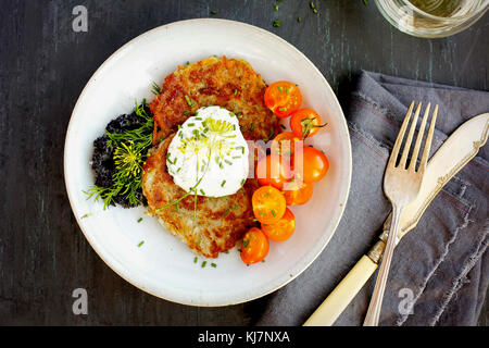 Potato Provolone Cakes served with Dill Creme, Cherry Tomatoes, Kale and White Wine. Photographed on a grey background. Stock Photo