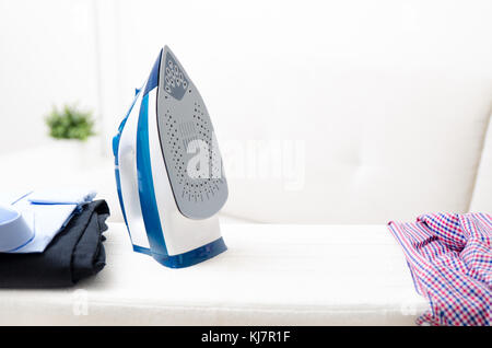 Steam blue iron on ironing board. Clothes, ironing board household concept Stock Photo
