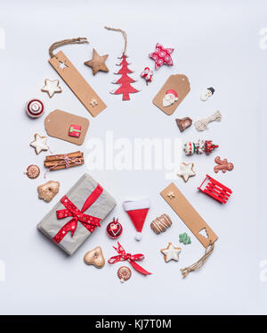 Round Christmas frame layout composition for greeting card with craft paper , tags and gifts, holiday cookies, chocolate, gingerbread and red festive  Stock Photo