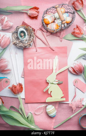 Easter greeting layout with tulips,eggs, and decor bunny on shopping bag on pastel color background Stock Photo