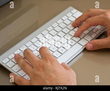 Hands typing on the remote wireless computer keyboard - using technology - enter login, password and credentials concept Stock Photo