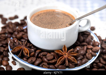 Composition of a coffee cup with spreaded beans and star anise. Stock Photo