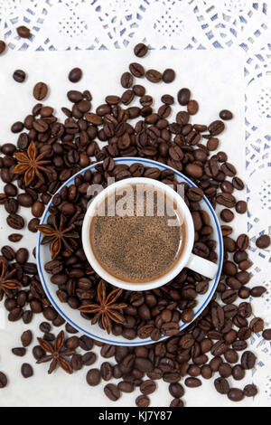 Composition of a coffee cup with spreaded beans and star anise. Stock Photo